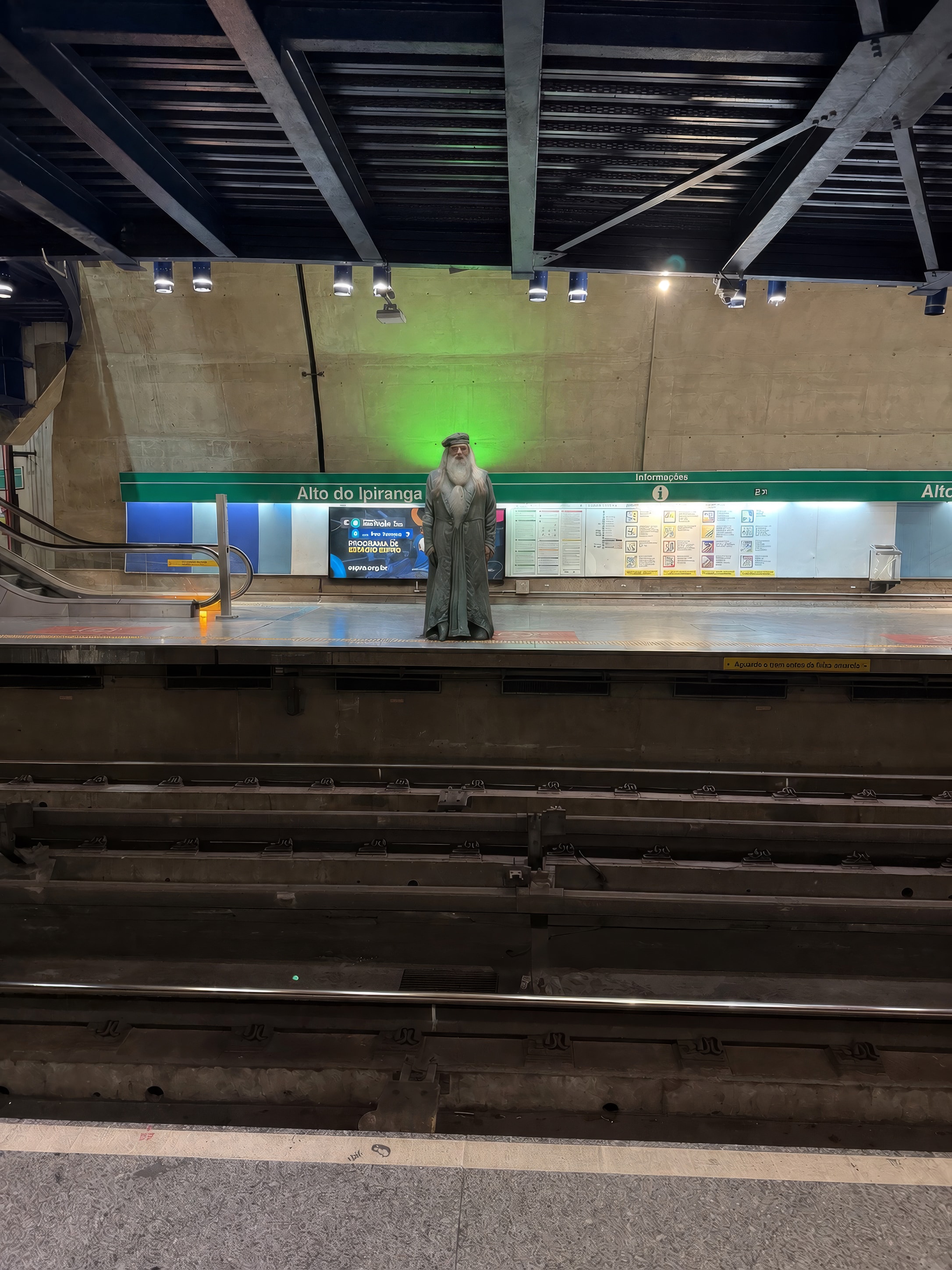 Mago de vestes e chapéu escuros parado na plataforma de uma estação de metrô, sob luz esverdeada